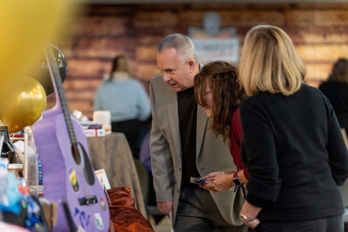 Guests at the 2023 Comedy and Cocktails inspect the wide variety of silent auction items.